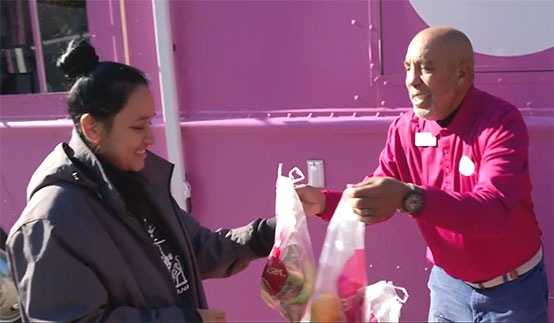 Man handing out food to a woman at a mobile food bank